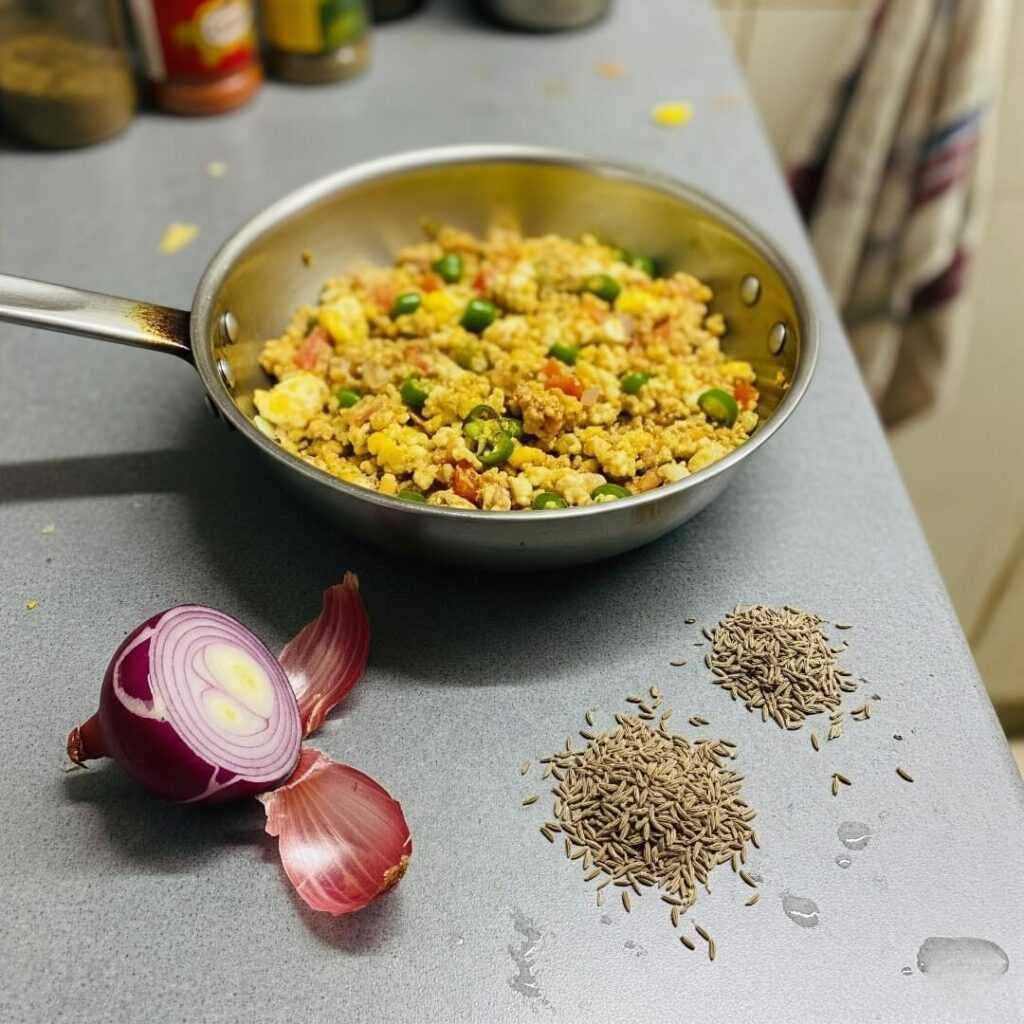 Messy kitchen counter with egg bhurji and spilled cumin.