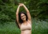 The Best Pregnancy Exercises for Each Trimester Pregnant woman stretching in park.